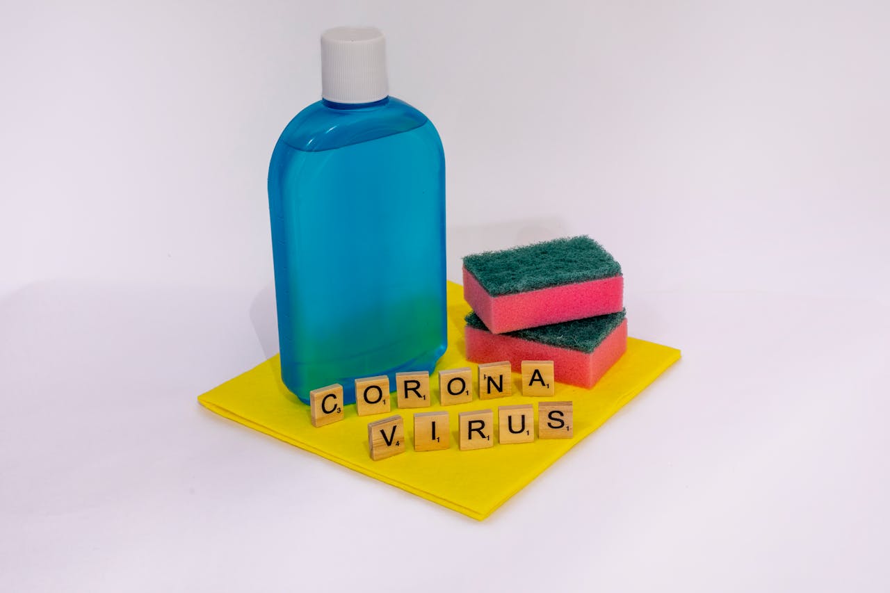 services-01 Cleaning products with scrabble tiles spelling coronavirus on a white surface.