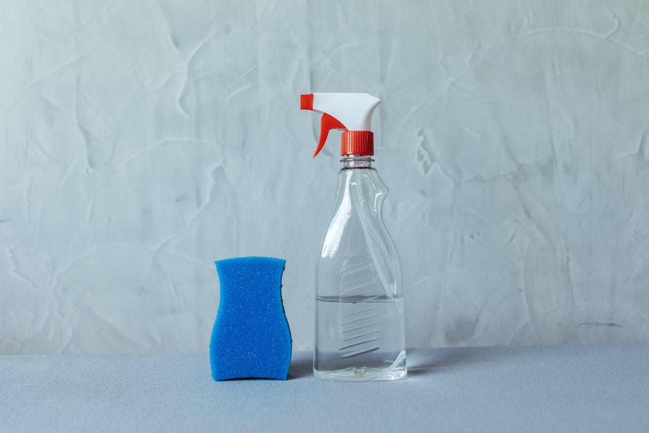 services-02 A spray bottle and blue sponge on a textured grey surface. Perfect for cleaning themes.